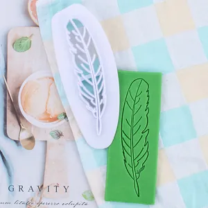 Gedetailleerde veer-fondantsteker en reliëf op groen deeg op een geruite achtergrond doek