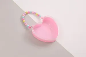 Rosa herzförmige Geschenkschachtel mit einem farbenfrohen Griff aus Pastellperlen.