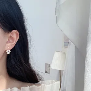 Nahaufnahme eines eleganten Katzenpfoten-Perlenohrrings am Ohr mit weichem Hintergrund
