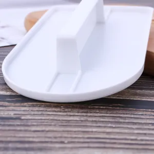 Primo piano di uno spatola per fondente in plastica bianca con maniglia per torte