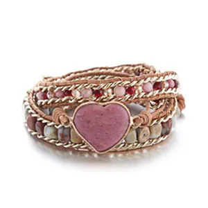 Detalle de una pulsera envolvente hecha a mano con piedra de corazón rosa y abalorios.