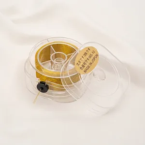 Detailed view of high-quality golden metallic thread spool in a clear storage box