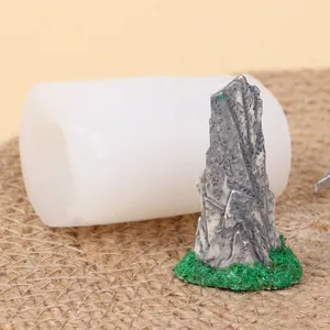Detail of white silicone mold next to finished miniature grey rock mountain ornament
