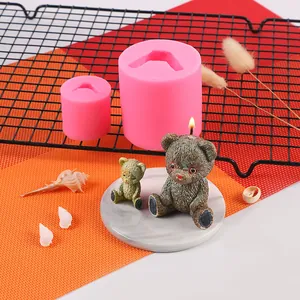 Close-up of pink silicone teddy bear molds with finished wax candles on display.