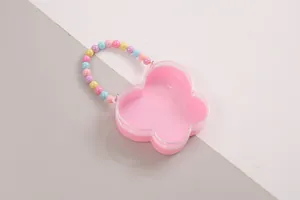 Detailansicht einer rosa Geschenkbox in Blumenform mit buntem Perlengriff für Kinder.