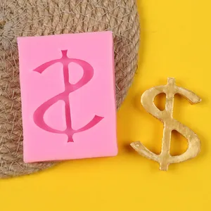 Detailed view of pink dollar sign silicone mold next to a golden finished candy ornament