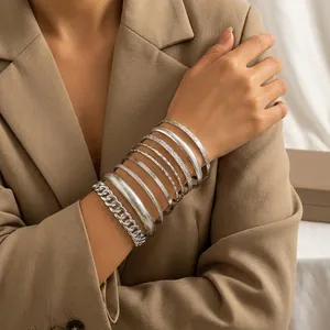 Primer plano de brazaletes plateados retro grabados y una pulsera de cadena gruesa apilados.