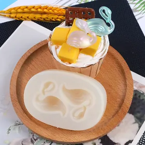 Translucent silicone swan mold shown with finished iridescent resin decorations on a cupcake