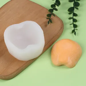 Detailaufnahme einer weißen Silikonform für Äpfel neben einer orangefarbenen Fruchtseife