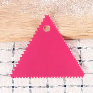 Close-up detail of a pink triangular serrated plastic scraper for DIY cake baking and decorating