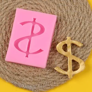 Close-up of pink dollar sign silicone mold with finished golden money decoration piece on mat
