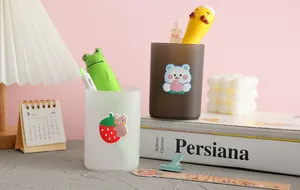 Detailed view of frosted pen holders with cute cartoon stickers on a desktop setup
