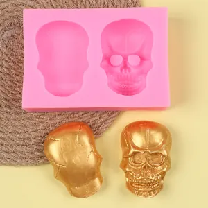 Close-up detail of a pink silicone skull mold with two gold-finished skull samples