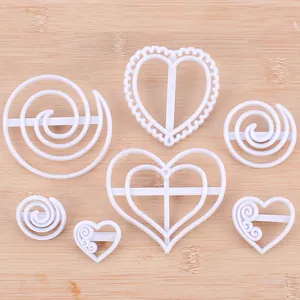 Set witte hart- en spiraalvormige koekjesuitstekers voor bakdecoratie op houten vlak.