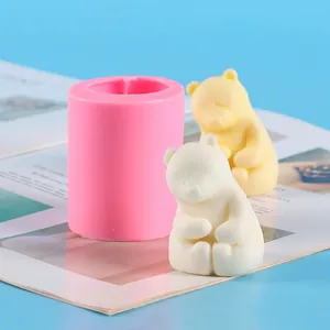 Detailed view of a pink silicone mold beside finished 3D teddy bear candle ornaments