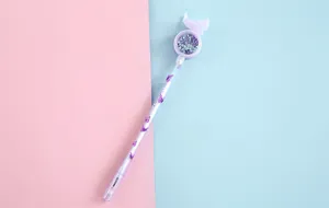 Detailed macro view of a purple gel pen featuring sequins and a butterfly top decoration