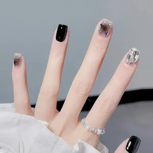 Nahaufnahme von schwarzen Sternen-Klebe-Nägeln mit Glitzer und luxuriösen Strasssteinen.