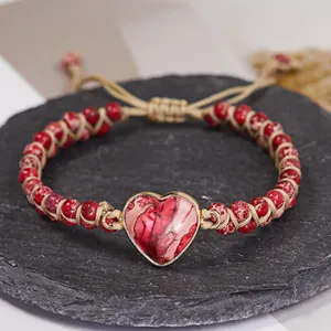 Primer plano detallado de pulsera de yoga hecha a mano con colgante de corazón de piedra.