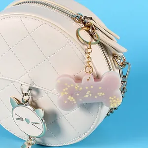 Detailansicht eines rosa Knochenanhängers aus Kunstharz an einer gesteppten Tasche