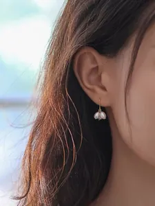 Primer plano de elegantes pendientes en forma de uva con perlas de agua dulce en una modelo.