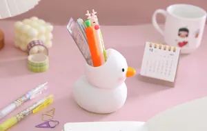 Primo piano di un simpatico portapenne a forma di anatra su una scrivania rosa