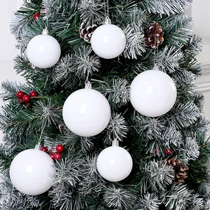 Nahaufnahme von weißen Weihnachtskugeln an einem weihnachtlich verschneiten Tannenbaum
