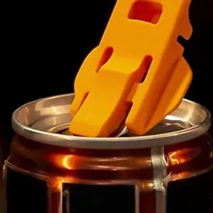 Primo piano di un apriscatole manuale arancione brillante utilizzato su una lattina.