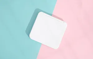 Compact white square portable makeup mirror closed on pastel blue and pink background