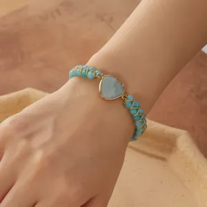 Primer plano de una pulsera trenzada de doble capa con una piedra azul en forma de corazón.