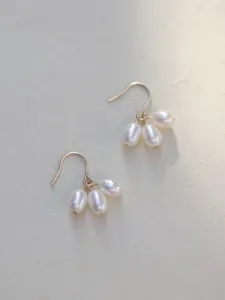 Primer plano de elegantes pendientes de racimo con perlas de agua dulce y ganchos dorados.