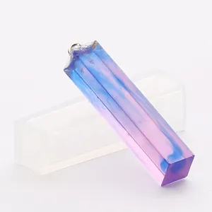 Vue détaillée d'un pendentif en résine à côté de son moule en silicone translucide