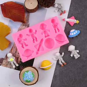 Close-up of pink silicone space mold with finished astronaut and rocket figurines.