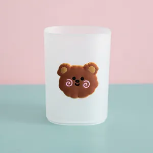 Close-up of a frosted transparent pen holder featuring a cute 3D cartoon bear decoration.