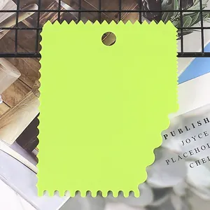 Detail view of a green serrated plastic cake scraper tool for baking and decorating
