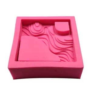 Dettaglio di uno stampo quadrato in silicone rosa con design astratto del paesaggio