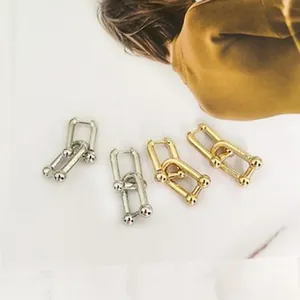 Primer plano detallado de elegantes pendientes U-link en oro y plata con detalles de bola