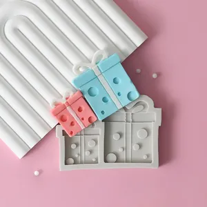 Primer plano de un molde de silicona para cajas de regalo con muestras de fondant rosa y azul