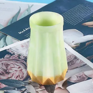 Close-up of a faceted green resin vase with gold base on floral background