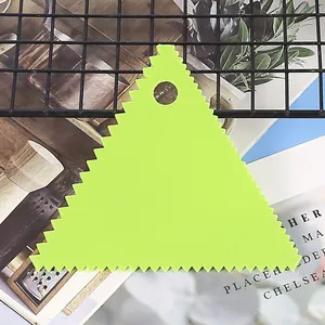 Close-up detail of a lime green triangular plastic scraper with serrated edges for baking.