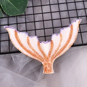 Detail shot of a white and gold resin mermaid tail with purple edges