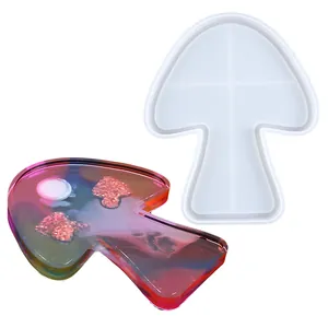 Dettaglio dello stampo in silicone a fungo accanto a un vassoio in resina colorata