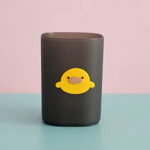 Close-up of a semi-transparent black pencil holder with a cute yellow duck ornament.