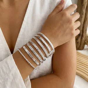 Vista detallada de brazaletes de plata retro con patrones grabados y diseño trenzado