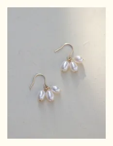 Detalle de pendientes minimalistas de oro de 14K con perlas de agua dulce tipo arroz.
