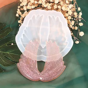 Detail view of wing-shaped silicone mold and finished pink glitter resin wing