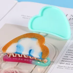 Detail view of heart-shaped silicone mold and finished resin hair clip accessories