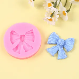 Primer plano de molde de silicona para lazos y un lazo de fondant azul claro terminado
