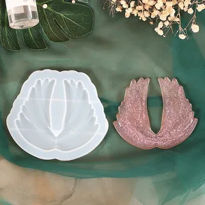 Detailed view of a silicone mold and finished pink glitter wing-shaped resin craft.