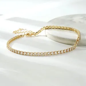 Close-up of a gold-plated tennis chain anklet with sparkling cubic zirconia stones.