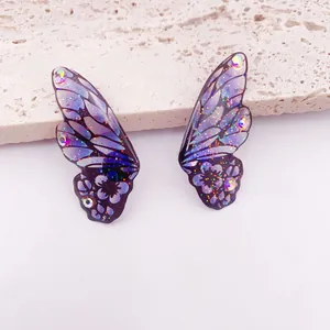 Primo piano di orecchini ad ala di farfalla viola con strass scintillanti e glitter